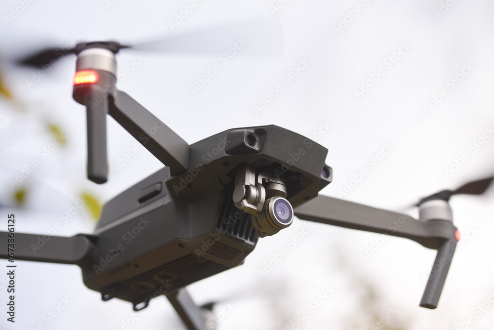 Drone quadcopter with digital camera and fast rotating propellers flying taking video and pictures. Greenery backgroud
Drone quadcopter with digital camera and fast rotating propellers flying taking video and pictures. Greenery backgroud