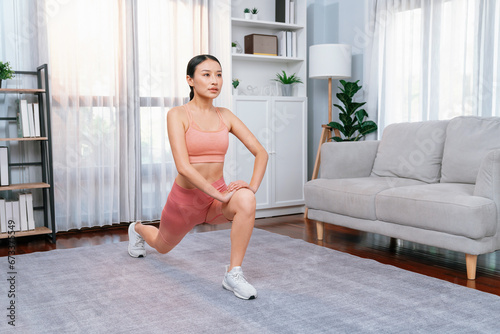 Fototapeta Naklejka Na Ścianę i Meble -  Young attractive asian woman in sportswear stretching before fitness exercise routine. Home body workout with healthy athletic woman warming up. Vigorous
