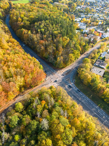 Aerial view of a crossroad between the colourful autumn trees