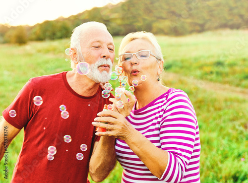 woman man outdoor senior couple happy fun retirement together bubble soap blowing love old nature mature