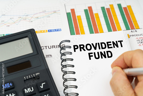 There is a calculator on the table, business charts, a man made a note in a notebook - PROVIDENT FUND photo