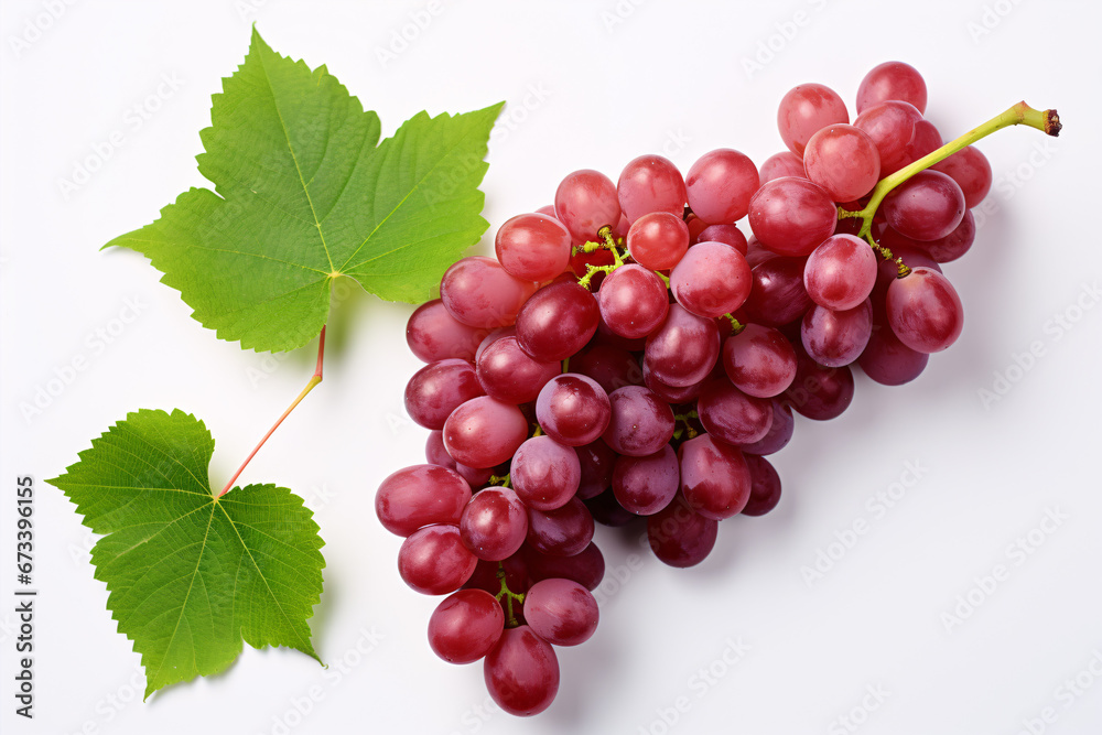 Fototapeta premium Isolated top view of partially sliced red grapes surrounded by green foliage on a white background.