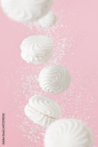Soaring white zephyr marshmallow on pink background with sugar powder flying food levitation