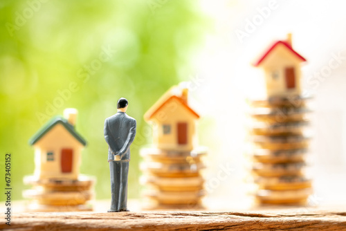 Businessman model standing on stack gold coin with grow value with working capital management and home model is destination in the garden, Loan and business investment for real estate concept.