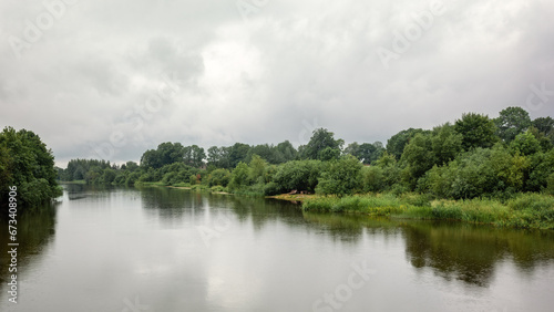 Lithuanian river on the banks of green foliage  view on a cloudy day with light rain