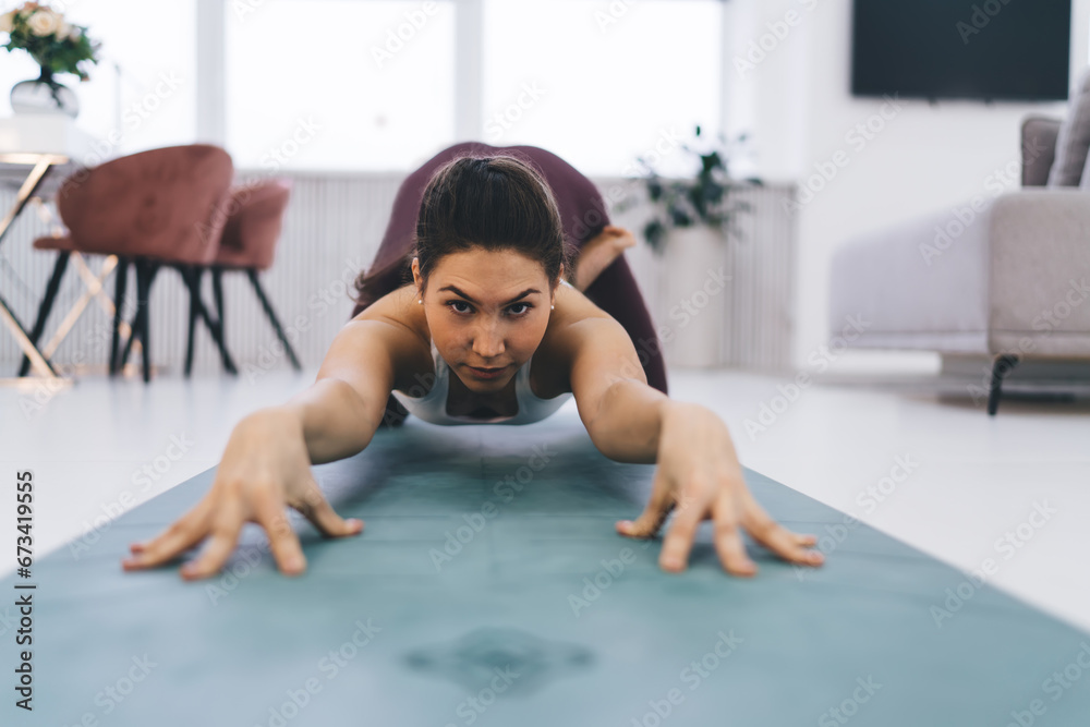 Focused female doing Extended Puppy pose on mat at home