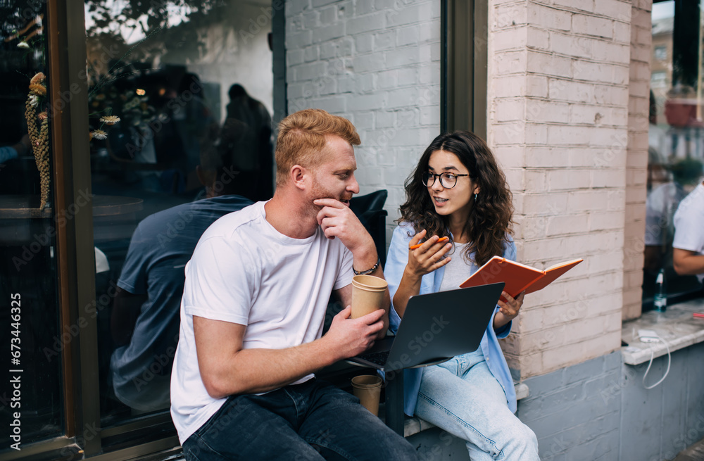 © BullRun - Positive colleagues discussing work issues in street cafe during lunch