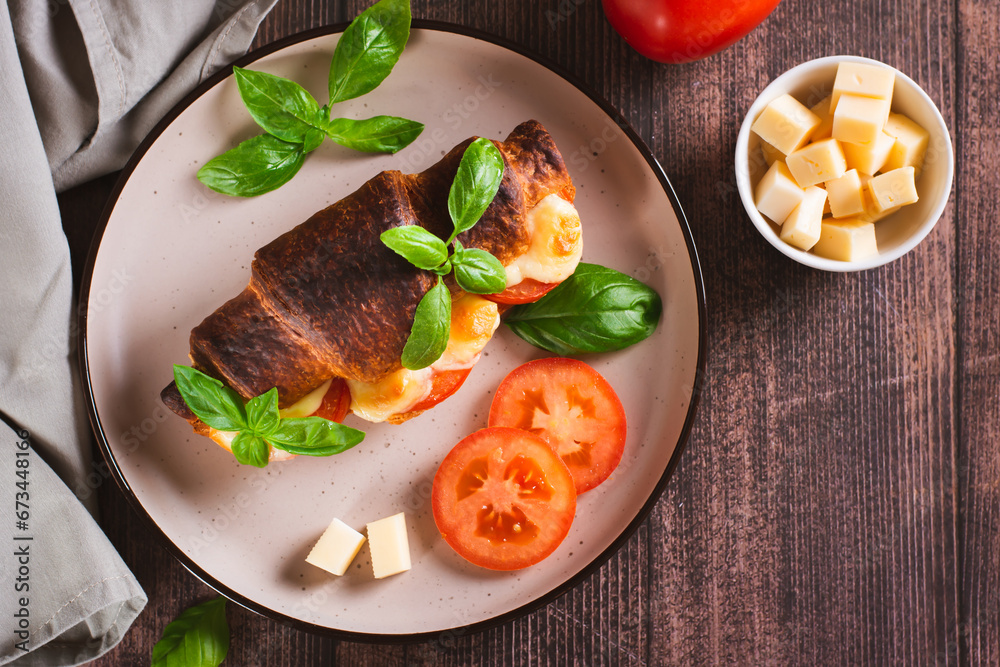 Croissant caprese sandwich baked with tomatoes and cheese on a plate top view