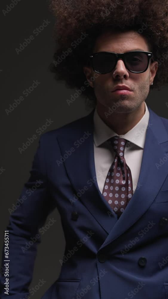 vertical video of handsome elegant man holding hands in pockets, looking to side, looking forward and making silence gesture on grey background vertical video of handsome elegant man holding hands in pockets, looking to side, looking forward and making silence gesture on grey background