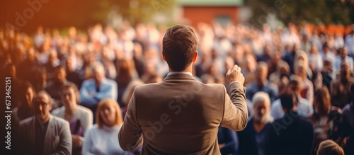 Speaker viewed from the back is giving a speech while the whole audience is listening to him at business conference