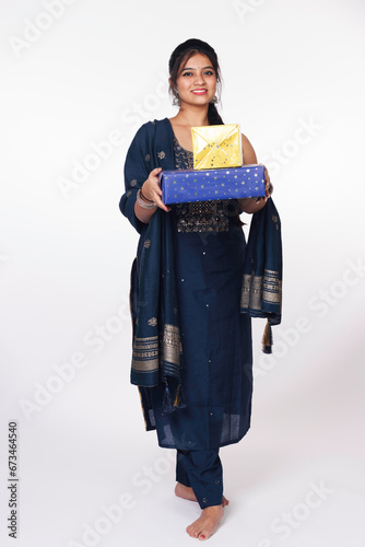 Portrait of young Indian woman or girl in a traditional dress carrying gift box during festival isolated over white background