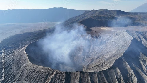 Aerial 4K footage of the Bromo volcano crater caldera with smoke coming. An active volcano in Tengger Semeru National Park in East Java, Indonesia. photo