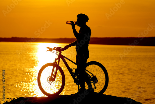 A man standing next to a bike on top of a rock. Man Surrounded by Nature's Beauty