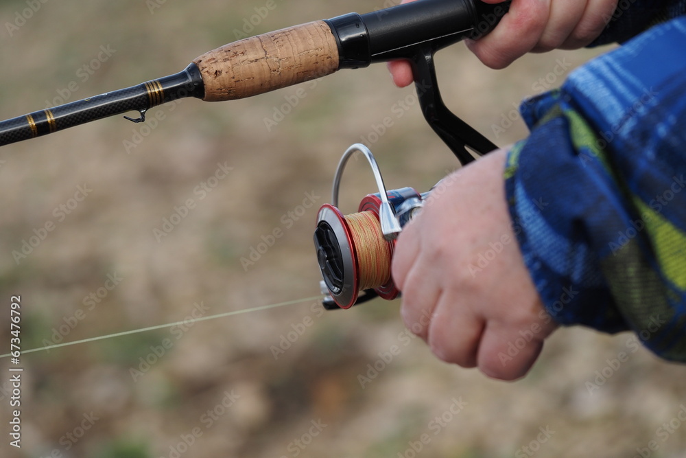 Fishing. A spinning rod with a reel in the hands of a fisherman. Close-up. High quality photo Fishing. A spinning rod with a reel in the hands of a fisherman. Close-up. High quality photo