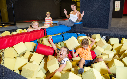 Playful happy children friends spending time together having fight with foam cubes, throwing them at each other in indoor kids entertainment centrer