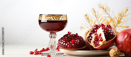 On a white background a sacred cup filled with wine pomegranate and honey symbolizes the Rosh Hashanah festivities which mark the Jewish New Year