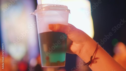Glass of cocktail in woman's hand at party concert convention music festival. photo