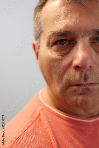 Close up of mid aged male face partially out of the frame wearing orange t-shirt photo