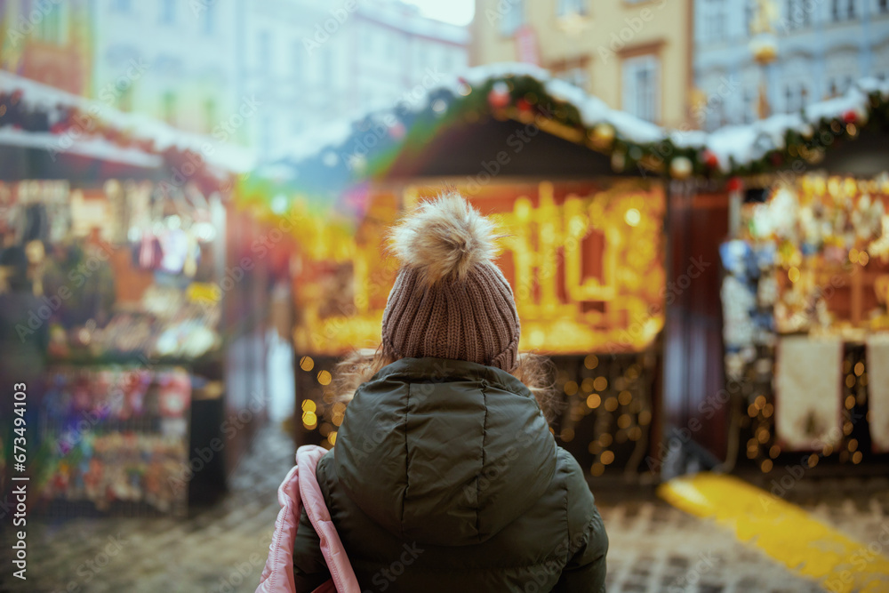 woman in green coat and brown hat at christmas fair in city