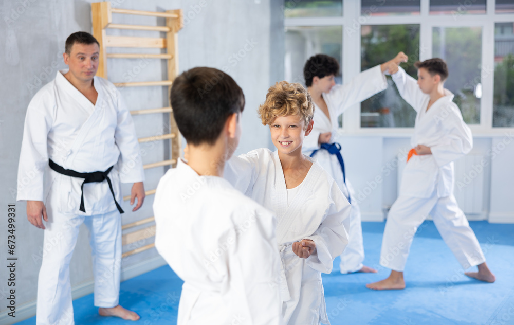 Fototapeta premium Diligent preteen karate students practicing fighting techniques during workout session