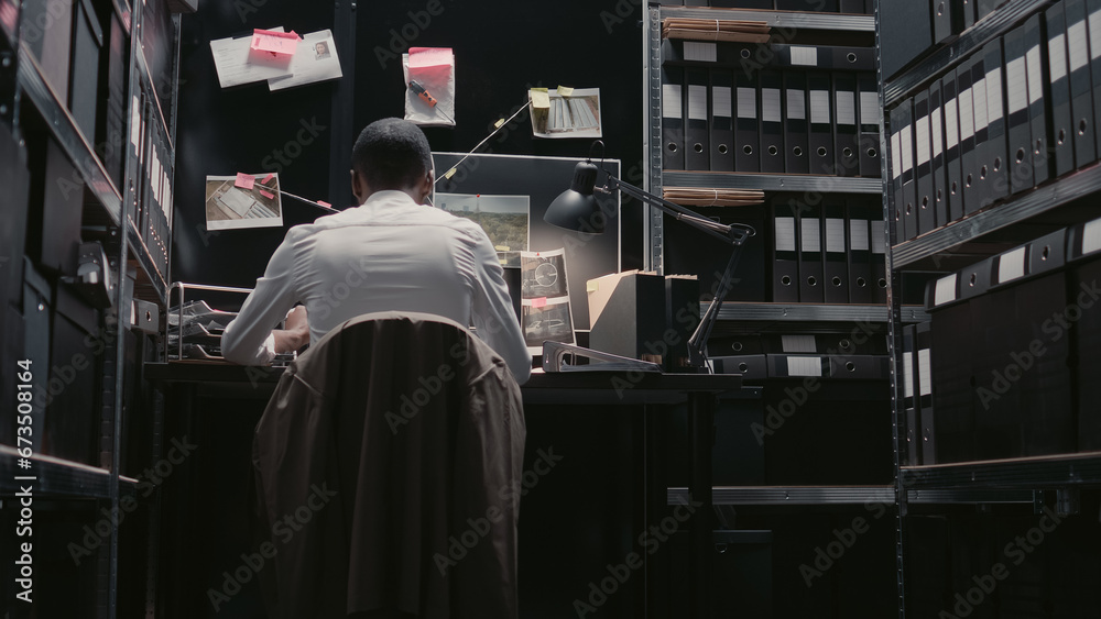 Police inspector analyzing forensic evidence on map, looking at professional detective board to solve crime. Male officer using background checks and records in incident room. Handheld shot. Police inspector analyzing forensic evidence on map, looking at professional detective board to solve crime. Male officer using background checks and records in incident room. Handheld shot.