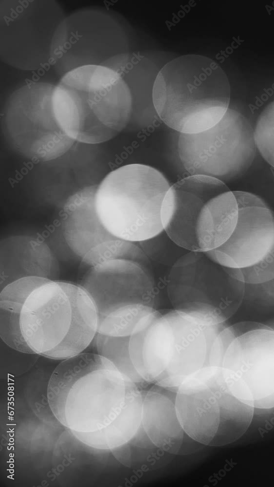 White bokeh in dark backround. Overlay, light leak, lens flare, or bokeh on black background.  Vertical, vertical video background.