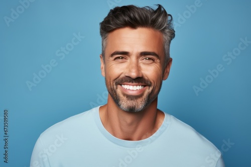 Portrait of handsome smiling man looking at camera and standing against blue background