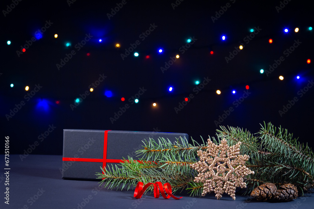 Christmas tree, decorations, lights and a gift box on a black background