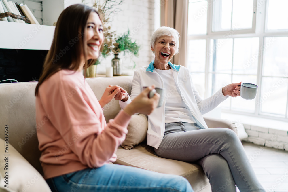 Cheerful multiethnic women laughing while sitting on couch Cheerful multiethnic women laughing while sitting on couch