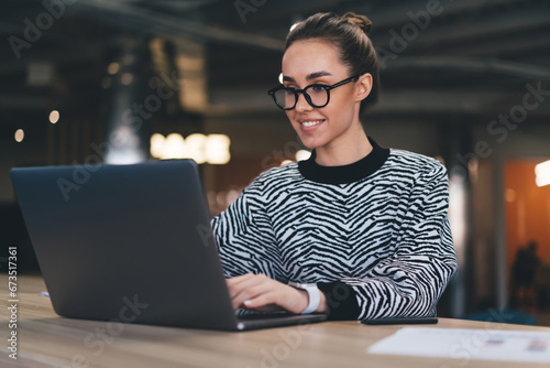Cheerful young woman working on laptop in cafe photo