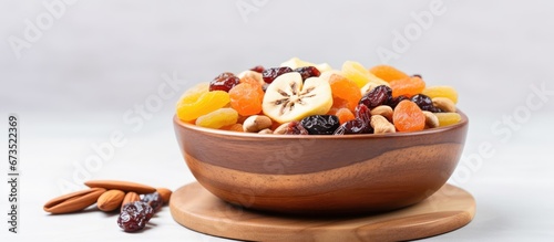 A wooden base holds a bowl filled with a mixture of nuts and dried fruits photo