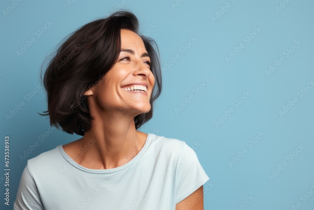 Portrait of a happy young woman laughing and looking up, isolated over blue background Portrait of a happy young woman laughing and looking up, isolated over blue background