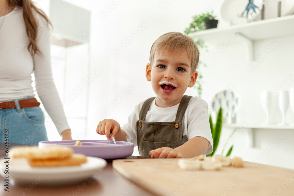 funny little boy eats milk breakfast in the kitchen and looks at the camera with an open mouth funny little boy eats milk breakfast in the kitchen and looks at the camera with an open mouth