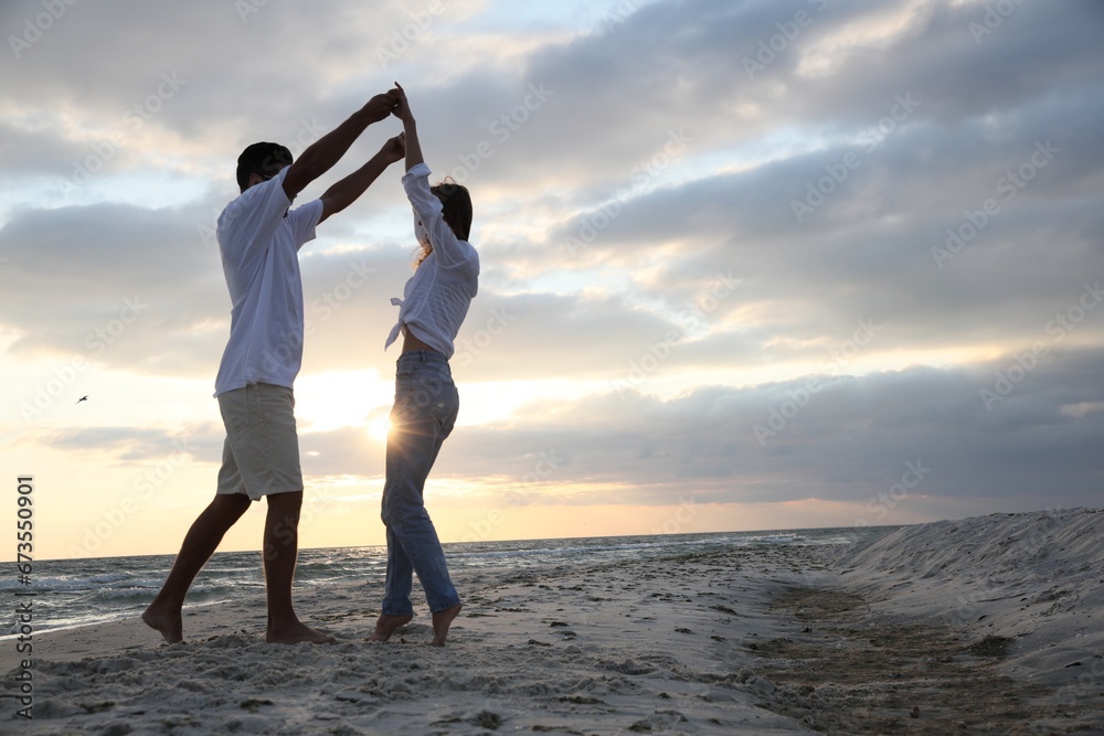 Fototapeta premium Happy couple dancing on beach at sunset