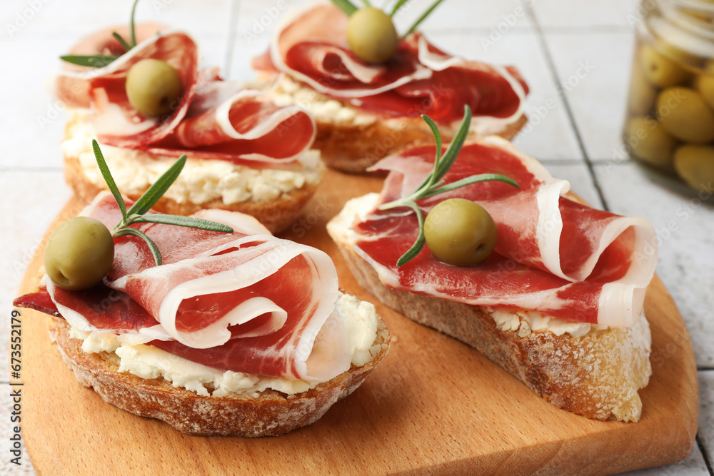 Tasty sandwiches with cured ham, rosemary and olives on wooden board, closeup