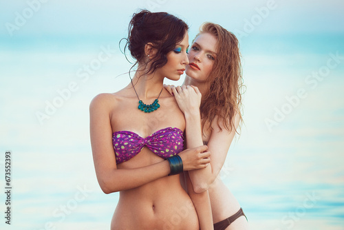 Happy together concept. Beautiful couple of models with perfect arty make-up in bikini at the seaside. Long wet hair and waterproof decorative cosmetics. Summer evening. Vintage style. Outdoor shot