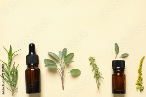Bottles of essential oils and different herbs on beige background, flat lay. Space for text