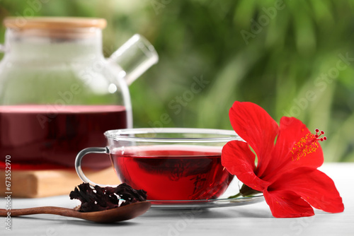 Delicious hibiscus tea and flowers on white wooden table outdoors  closeup