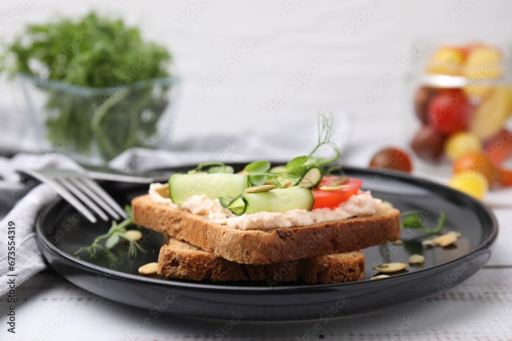Tasty vegan sandwich with cucumber, tomato and pumpkin seeds on white wooden table, closeup Tasty vegan sandwich with cucumber, tomato and pumpkin seeds on white wooden table, closeup
