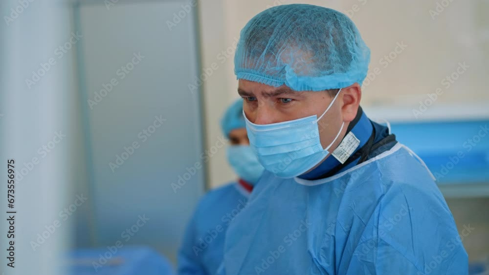 Male Caucasian doctor looking attentively in front of him. Portrait of a focused surgeon during operation. High angle view. Blurred backdrop. Male Caucasian doctor looking attentively in front of him. Portrait of a focused surgeon during operation. High angle view. Blurred backdrop.