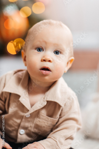 Boy child close-up against a background of garland lights. Portrait of a baby against the background of a Christmas tree and garlands. The first Christmas in a child's life