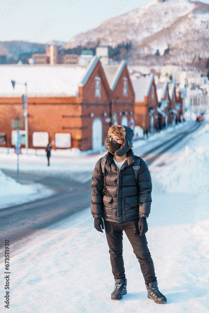 Man tourist Visiting in Hakodate, Traveler in Sweater sightseeing Kanemori Red Brick Warehouse with Snow in winter. landmark and popular for attractions in Hokkaido, Japan.Travel and Vacation concept