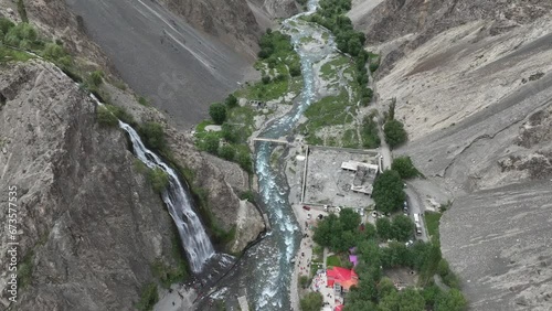 Circular drone flying over Mantoka waterfall in pakistan in Skardu Looking over waterfall and people and lake in beautiful landscape photo
