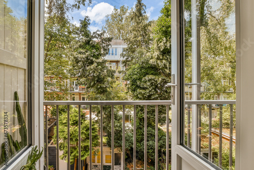 an outside area with trees and buildings in the background, taken from inside a window looking out onto a balcony