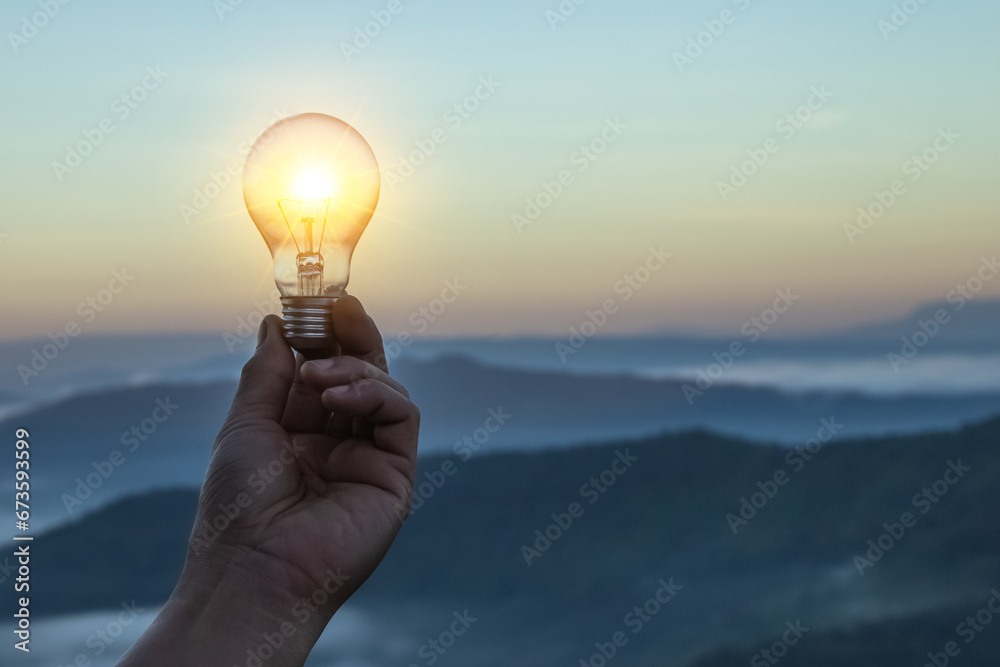 Close up electric light bulbs and switch on to yellow lights glowing on blurred and bokeh reflection lighting background. Hand holding light bulb. Lamp idea concept with innovation and inspiration. - obrazy, fototapety, plakaty 