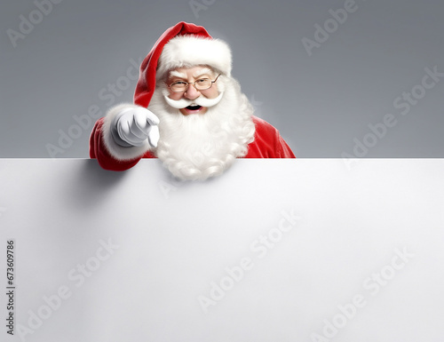 Smiling Santa Claus pointing at empty white advertising banner background with copy space