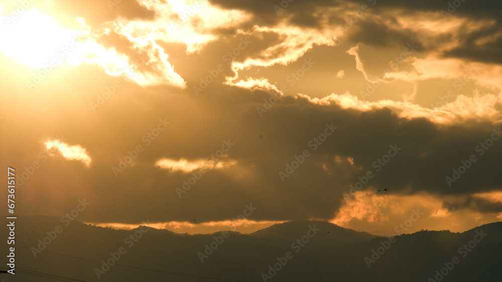 Beautiful dramatic sky with clouds at sunset or sunrise. Sunset sky at dusk in the evening with natural sky background with golden orange clouds.