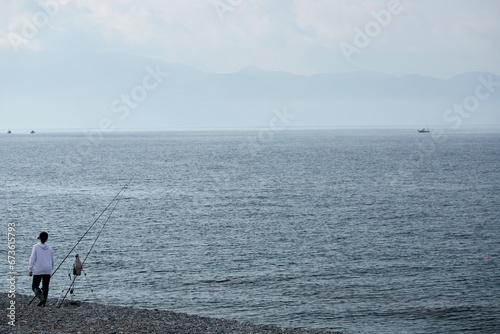 朝の海岸で海釣している若い女性の姿