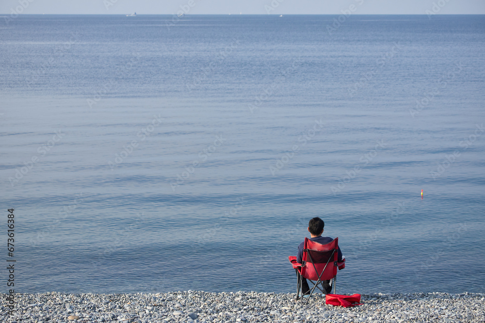 Naklejka premium 朝の海岸で海釣している男性の姿