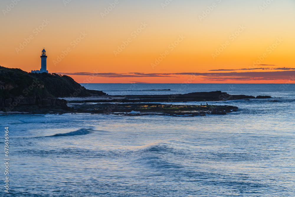 Sunrise seascape with lighthouse in the distance